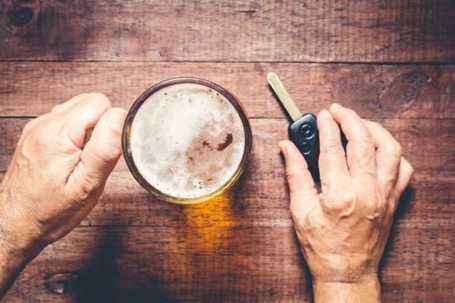 a hand holding a beer with another hand holding car keys